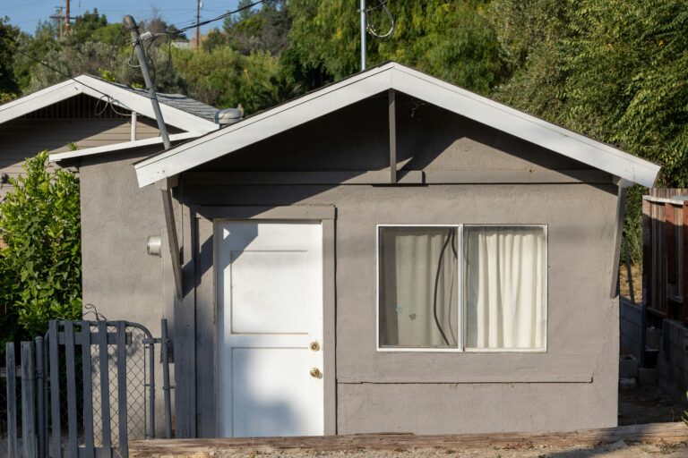 Charming small house with a sunlit facade and a simple door in a quiet village setting.